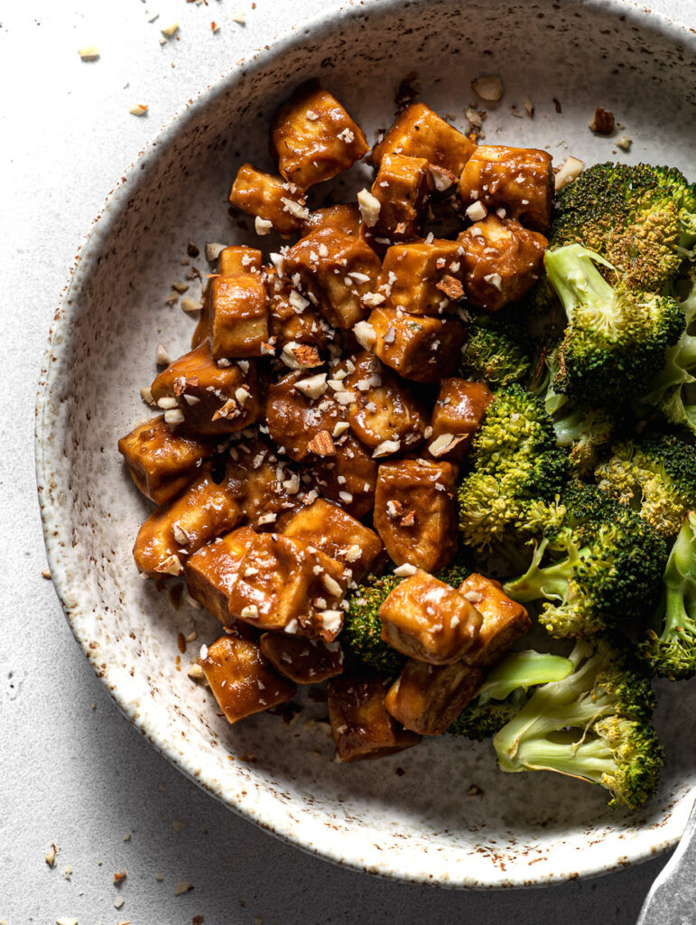 sheet pan tofu and broccoli in a large bowl with sesame seeds sprinkled around